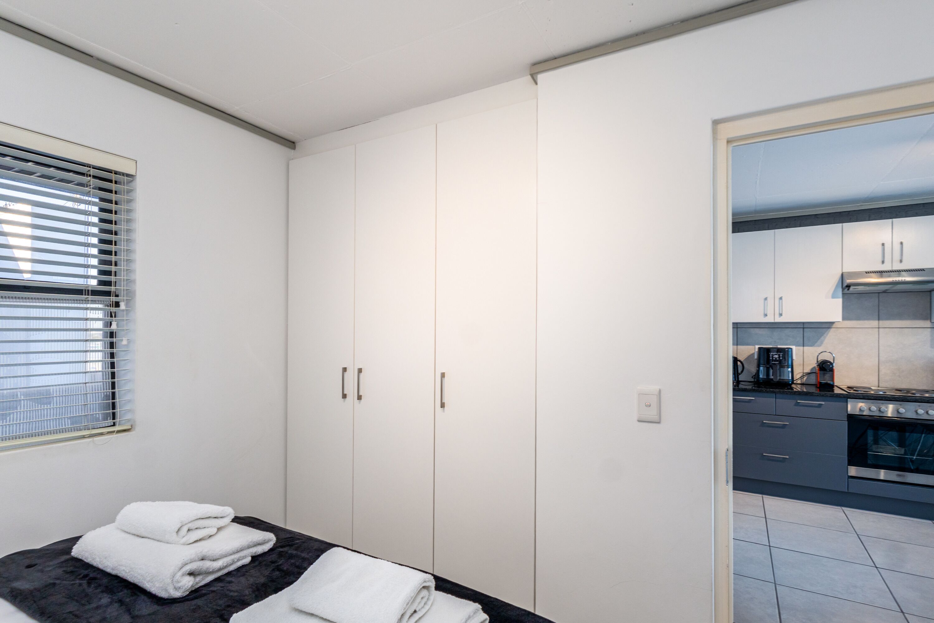 Une chambre à coucher avec un lit, une armoire et une vue sur la cuisine.