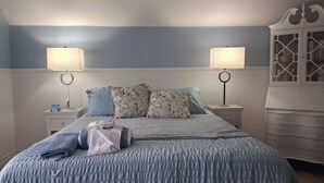 A bedroom with a bed, two bedside tables, a dresser, and two wall-mounted lamps.