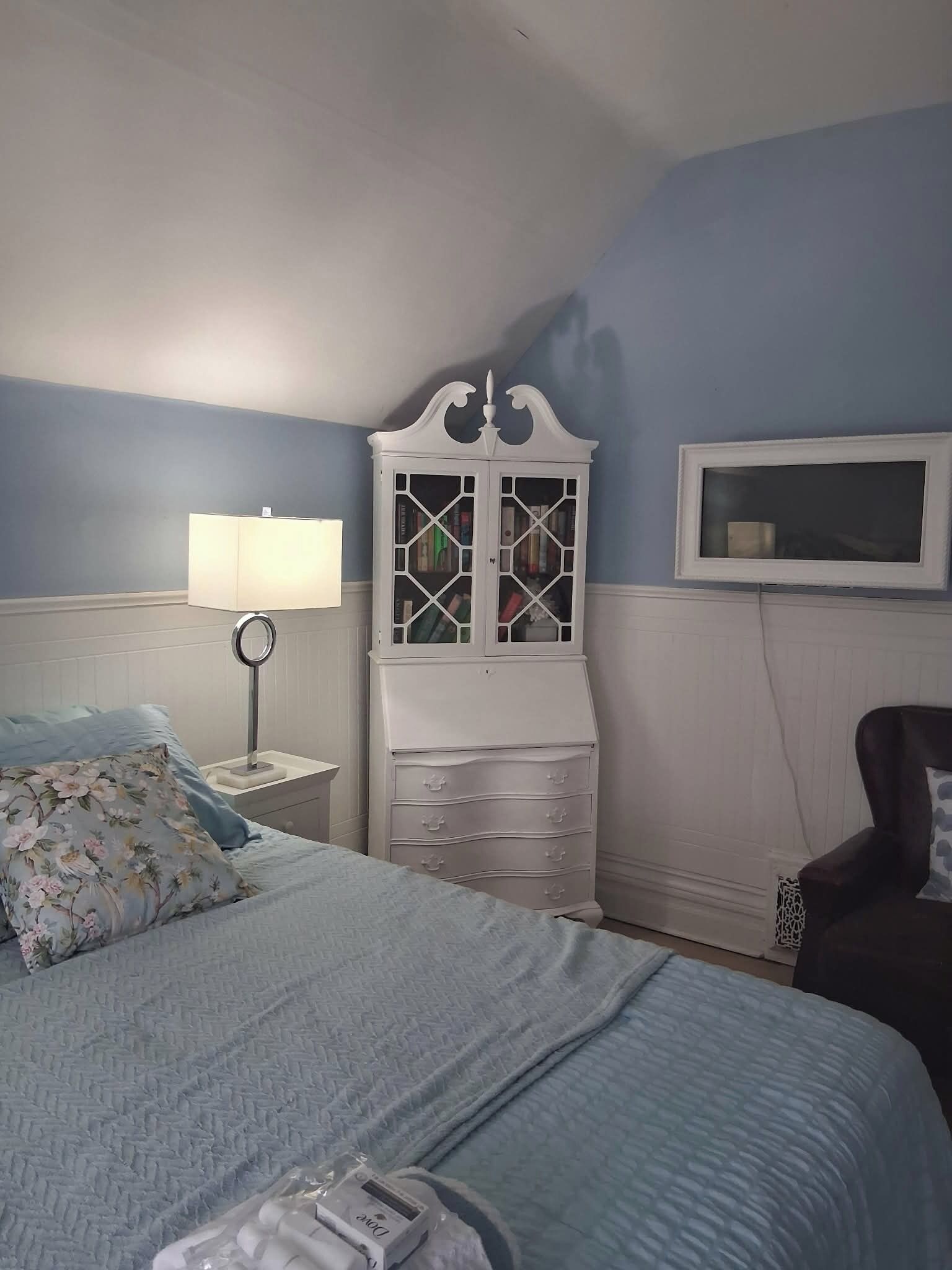 A bedroom with a bed, a dresser, a lamp, and a chair.
