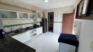 Eine Küche mit weißen Schränken, einer Mikrowelle, einem Kühlschrank und einem Spülbecken.