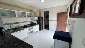 A kitchen with white cabinets, a microwave, a refrigerator, and a sink. - Vacation home in Porto das Dunas with pool. (Aquiraz)