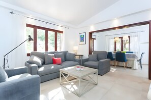 Ein modernes Wohnzimmer mit grauem Sofa, einem Couchtisch und einem Essbereich mit Tisch und Stühlen.