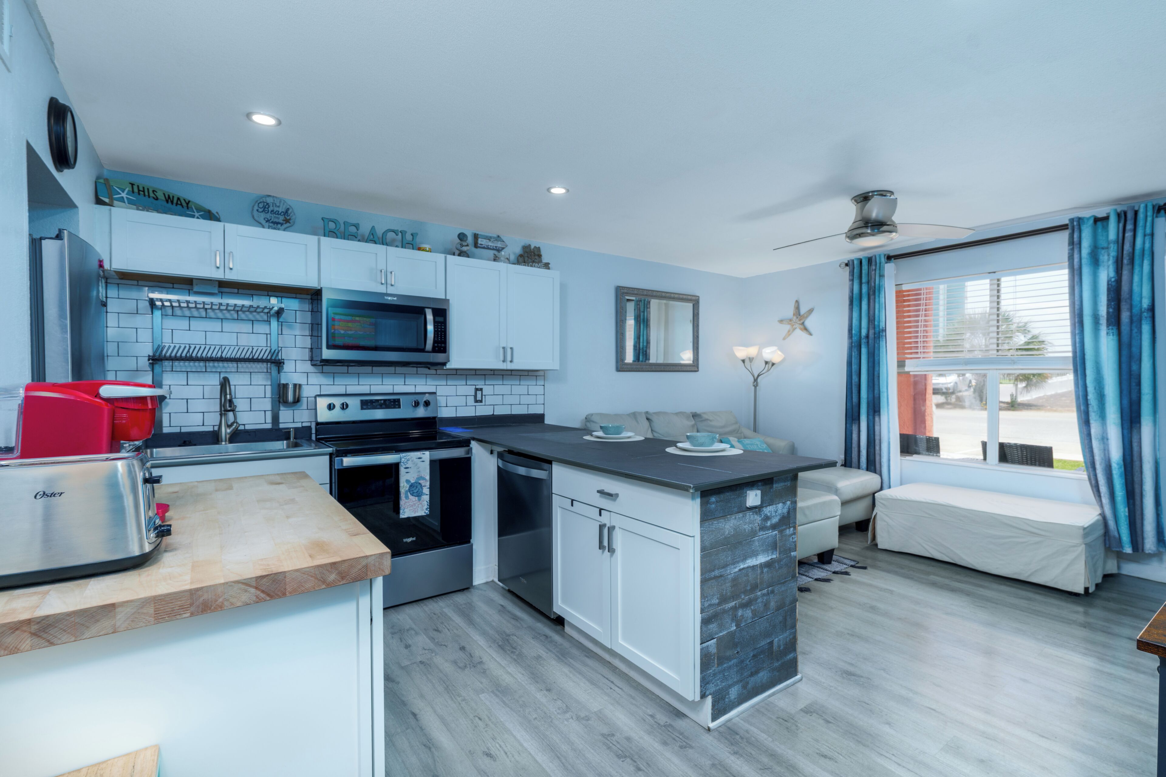 Une cuisine moderne équipée d’un four à micro-ondes, d’un grille-pain et d’un four. Un coin salon avec un banc et une décoration en forme d’étoile de mer est également disponible.