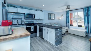 Una cucina moderna con forno a microonde, tostapane e forno. È presente una zona salotto con una panca e una decorazione a stella marina.