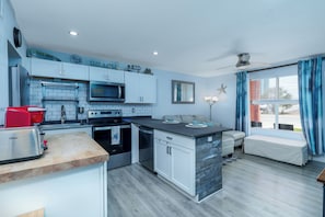 A modern kitchen with a microwave, toaster, and oven. There is a seating area with a bench and a starfish decoration.