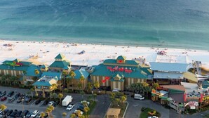 Vista aerea di un hotel con diversi edifici, un parcheggio e una spiaggia sullo sfondo.