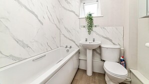 A bathroom with a bathtub, sink, and toilet, all in white. - 2 Bed Flat - Sleeps 3 - Pets - Parking - Wifi (Oxford)