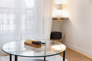 Une table en verre, une télécommande, un bol de raisins et une bougie.