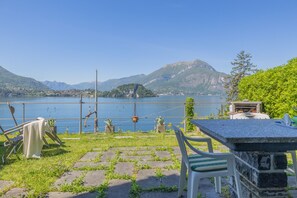 A terrace with a view of a lake and mountains, outdoor seating, and a stone table. - Casa Alpico Varenna by Varenna Holidays (Varenna)