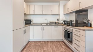 A modern kitchen with white cabinets, a microwave, a sink, and a coffee maker. - City Centre Luxury 1BDR Apt (Birmingham)