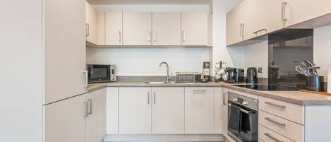 A modern kitchen with white cabinets, a microwave, a sink, and a coffee maker.