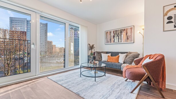 A modern living room with a large window, a round coffee table, a sofa, and a red chair. - City Centre Luxury 1BDR Apt (Birmingham)