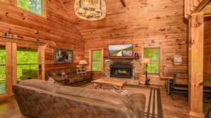 A cabin interior with a sofa, television, fireplace, and wooden walls. - Cozy Cabin in Pigeon Forge, Hot tub & Scenic Views (Pigeon Forge)