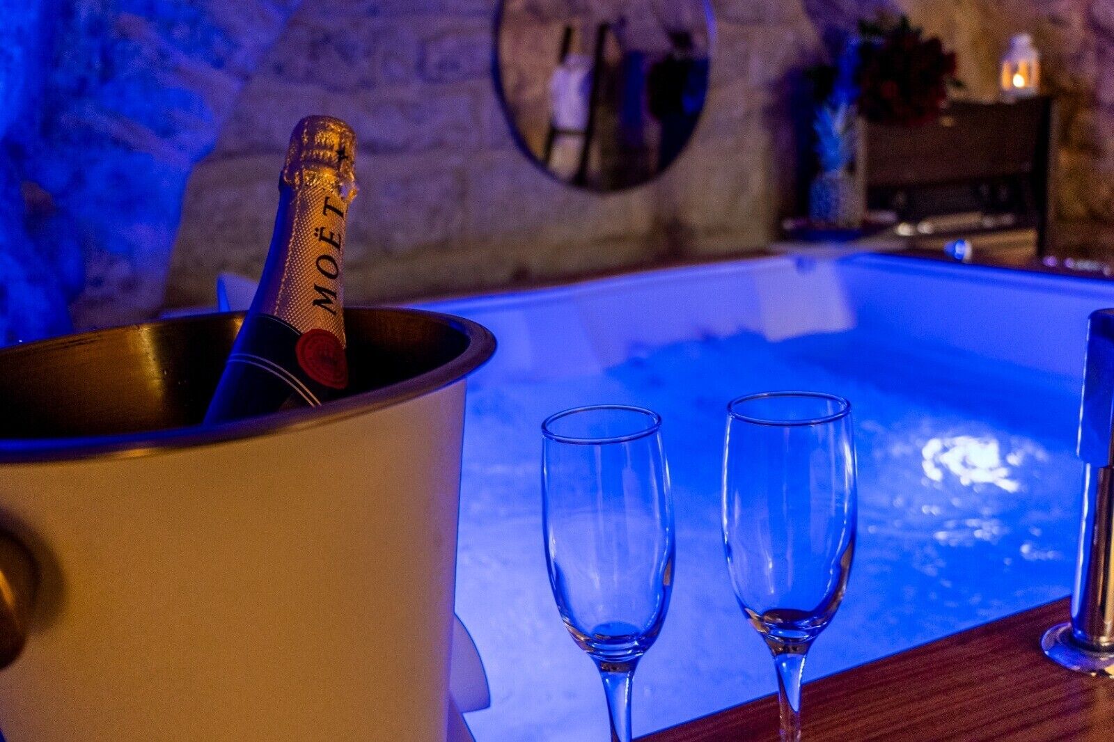 Una botella de champán en un balde, dos copas vacías y una piscina.