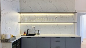 Een moderne keuken met een marmeren spatwand, verlichting onder de kastjes, een zwarte kraan en een inbouw wijnrek.