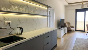Een moderne keuken met een marmeren spatwand, een ingebouwde wijnrek, een koffiezetapparaat en een flatscreen-televisie.