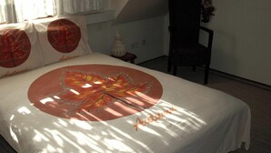 Un lit orné d’un motif de feuilles et sur lequel est posée une couverture avec le mot « Automne », une chaise et une fenêtre avec des rideaux.