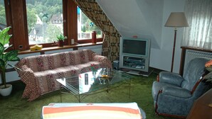 Un salon comprenant un canapé, un téléviseur, un fauteuil, une table basse et une lampe.