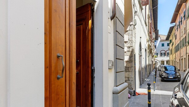 A narrow street with a wooden door, a building with a stone facade, and parked cars. - 'Ser Lapo - Dimora Ser Lapo' with Wi-Fi and Air Conditioning (Prato)
