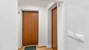A hallway with two wooden doors, a white wall, and a light switch. - 'Ser Lapo - Dimora Ser Lapo' with Wi-Fi and Air Conditioning (Prato)