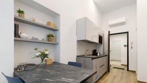 A compact kitchen with a marble countertop, built-in shelves, and a small dining area with chairs. - 'Ser Lapo - Dimora Ser Lapo' with Wi-Fi and Air Conditioning (Prato)