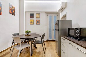 Una cocina funcional con una mesa de comedor, sillas, un refrigerador y un microondas.