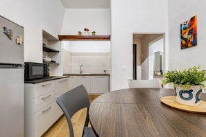 Une cuisine moderne avec des meubles blancs, un four à micro-ondes et un coin repas comprenant une table ronde et des chaises.