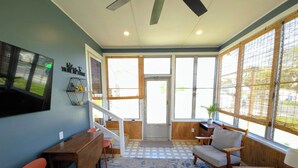 Una habitación con comedor, sofá, televisión montada en la pared y ventanas amplias.