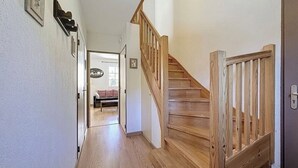 Een houten trap die leidt naar een slaapkamer met een bed en een hanglamp.