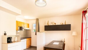 Een compacte keuken met een eettafel en stoelen, een ingebouwde oven en een magnetron.