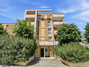 A multi-story residential building with a central entrance, balconies, and surrounding greenery. - Charming apartment for 4 people - near the sea (Grasse)