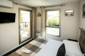 A hotel room with a bed, a TV, a window, and a view of the outside. - Elegant 2-room apartment with terrace in the center of Cannes (Cannes)