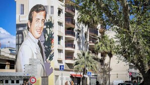 Un edificio con un grande murale raffigurante un uomo, balconi e un cielo azzurro intenso.