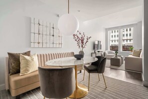 A modern living room with a sofa, round table, chairs, and artwork on the wall. - 17John: Superior 2 Bed W/D in unit + GYM + Lounge (New York)