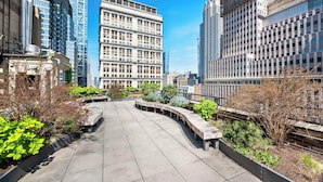Ein Dachgarten mit gewundener Wege, umgeben von Gebäuden unterschiedlicher Architektur.
