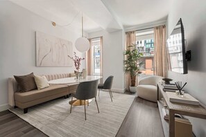 Una sala de estar moderna con sofá, mesa de comedor, sillas y un ventanal amplio.