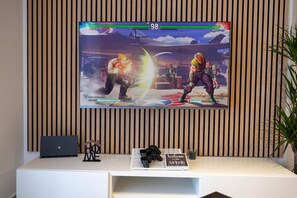 Ein an der Wand befestigter Fernseher zeigt ein Videospiel, in dem zwei Charaktere kämpfen.