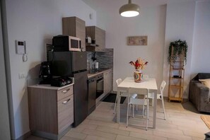 A compact kitchen with a microwave, coffee machine, and a dining area with a table and chairs.