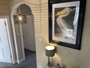 A hallway with a framed artwork of a pelican, a modern lamp, and a door leading to another room. - 62 North, Prime, Central, Stylish,  St Andrews 4 Bed 3 bathroom Townhouse (St Andrews)
