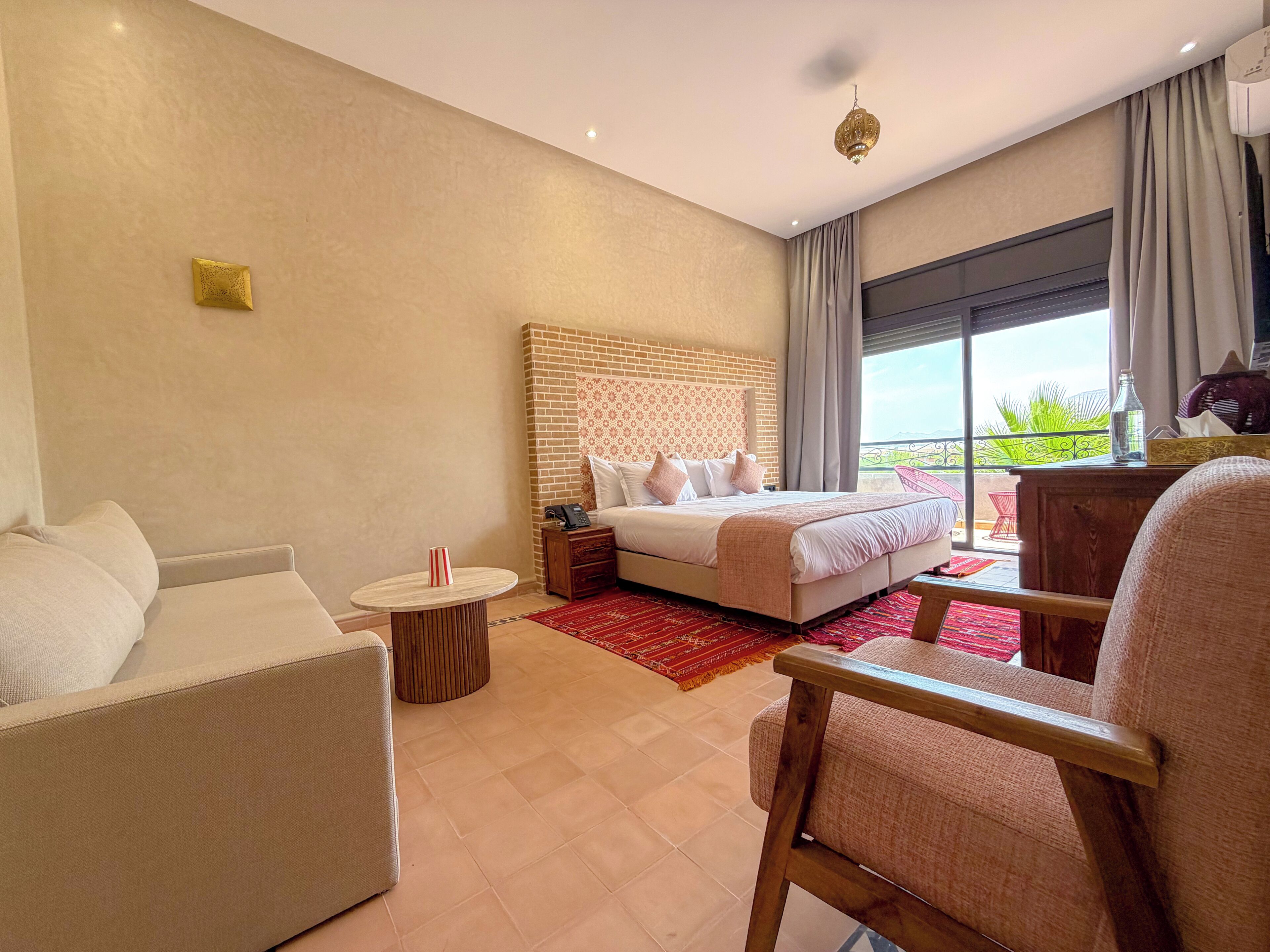 A hotel room with a bed, a sofa, a small table, and a chair.