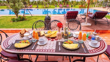 Mesa de comedor al aire libre, con piscina al fondo.