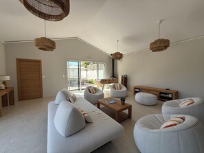 A spacious living room with a sofa set, ottomans, a wooden coffee table, and a TV stand. - Modern villa with a pool (Châtelaillon-Plage)