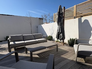 Una terraza con un sofá, sillas y una mesa.
