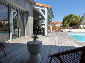 A wooden deck with a pool, outdoor seating, and a barbecue area. - Modern villa with a pool (Châtelaillon-Plage)