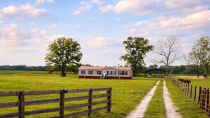 A rural landscape with a dirt path leading to a red-roofed building, surrounded by open fields and trees. - Amazing 3-bedroom home in charming O'Brien Florida (O'Brien)