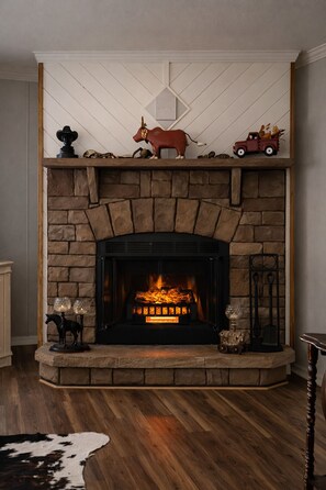 Una chimenea con detalles de piedra, un repisa decorada con adornos y una figurita de vaca.
