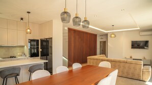 A modern kitchen with a central island, dining area with chairs, a sofa, and pendant lights. - Villa Elysium (Petrovac)