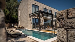A modern building with a swimming pool, outdoor seating, and a pergola. - Villa Elysium (Petrovac)