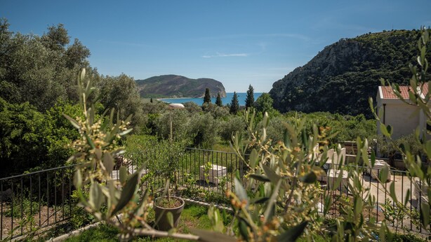 A view of a coastal landscape with a mountain, trees, and a building with a red roof. - Villa Elysium (Petrovac)