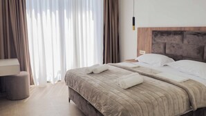 A hotel room with a bed, curtains, a bedside table, and a hanging light fixture. - Villa Elysium (Petrovac)